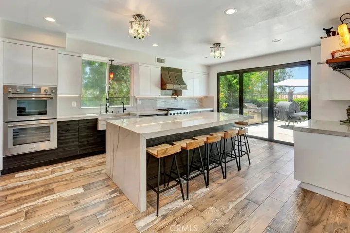 Spacious gourmet luxury kitchen featuring high-end appliances, elegant stone countertops, a large center island, and ample modern cabinetry perfect for everyday living, entertaining, and gatherings