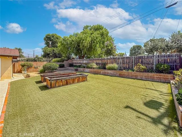 Backyard with synthetic grass and planters with sprinklers