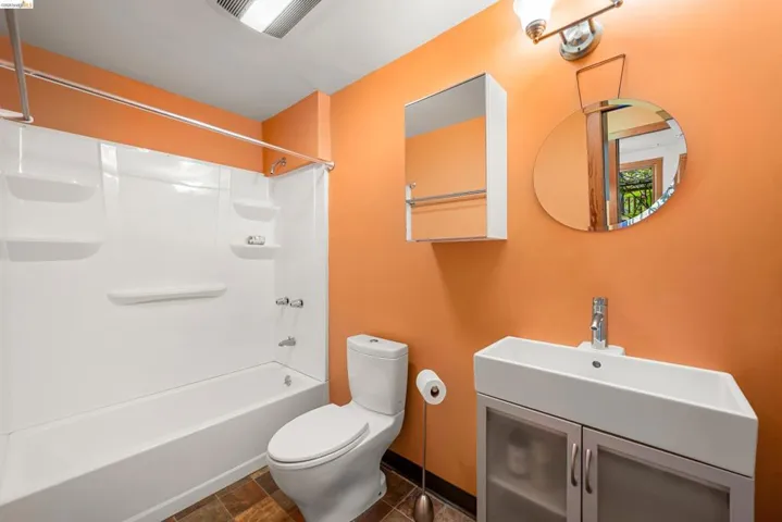 Contemporary bathroom featuring a white porcelain vessel sink with a single-handle chrome faucet, a coordinating white toilet, and a white tub/shower combination with integrated shelving