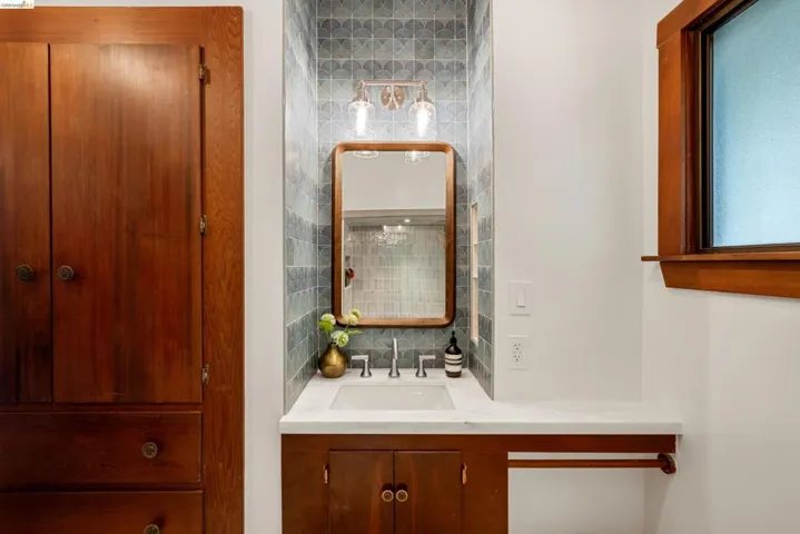 Bathroom vanity with a white rectangular undermount sink, brushed nickel faucet, and a light-toned countertop