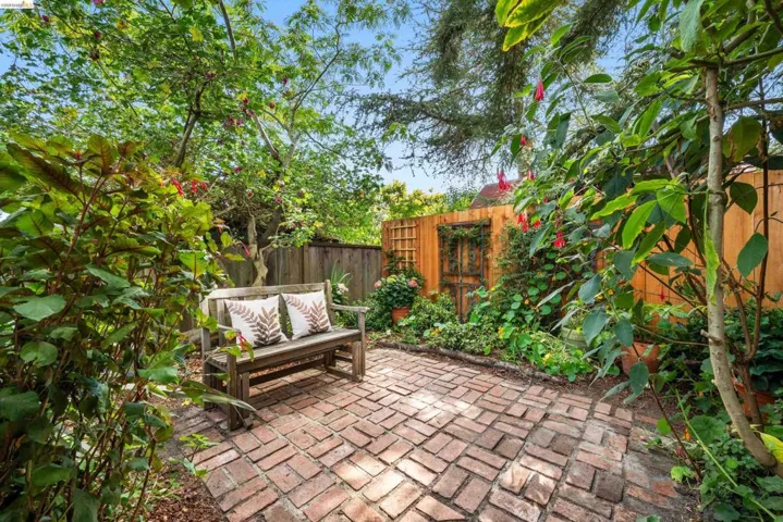 Private patio featuring a herringbone brick surface and perimeter landscaping