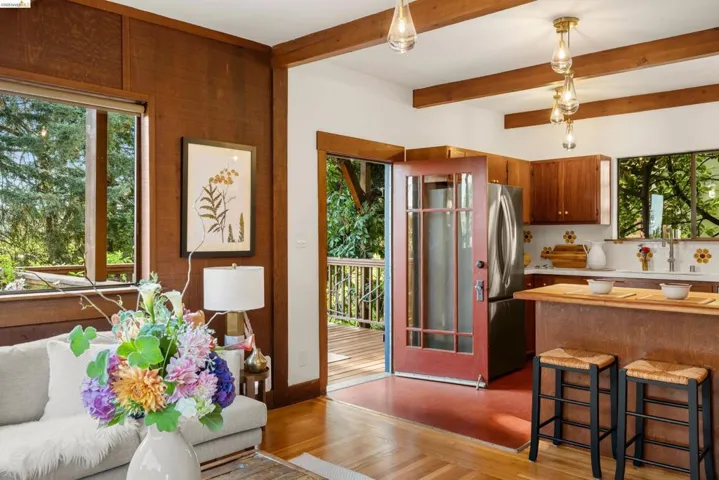 Open-concept living area featuring wood-paneled walls, exposed ceiling beams, and wood-finish flooring
