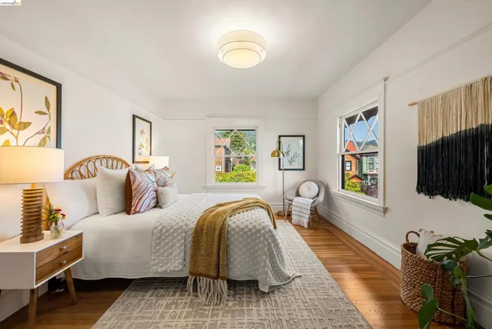 Bedroom featuring polished wood flooring, multiple windows with grid detailing, and a flush-mount ceiling light fixture