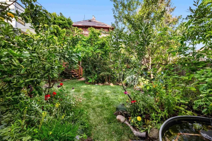 Lush, verdant backyard featuring a manicured lawn path, mature trees, and vibrant perennial plantings