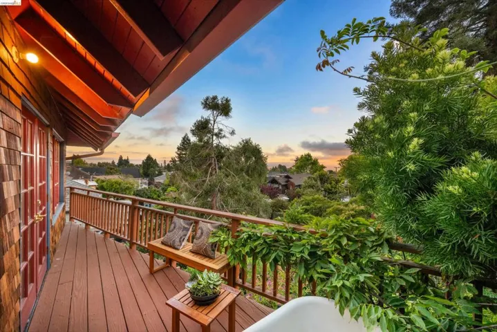 Expansive wood-plank deck featuring a wood railing system, shingle siding, red-framed doors, and an exposed wood soffit