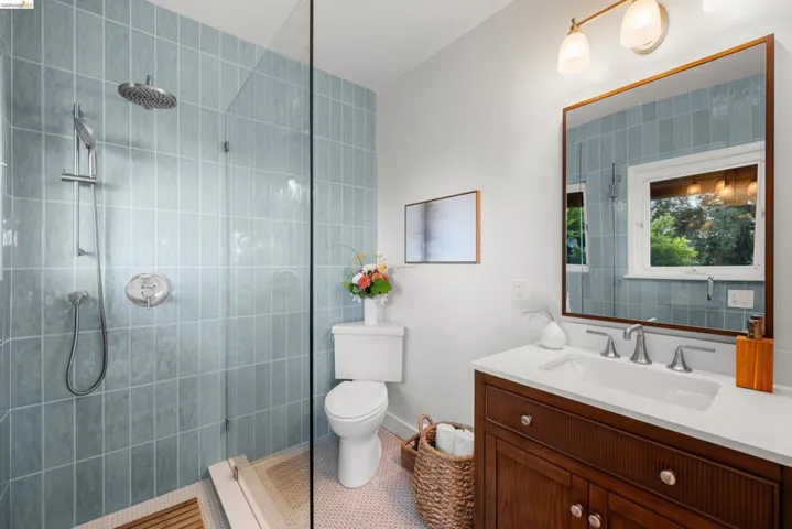 Contemporary bathroom featuring a glass-enclosed shower with blue vertical tile, a rain showerhead, and a handheld shower fixture