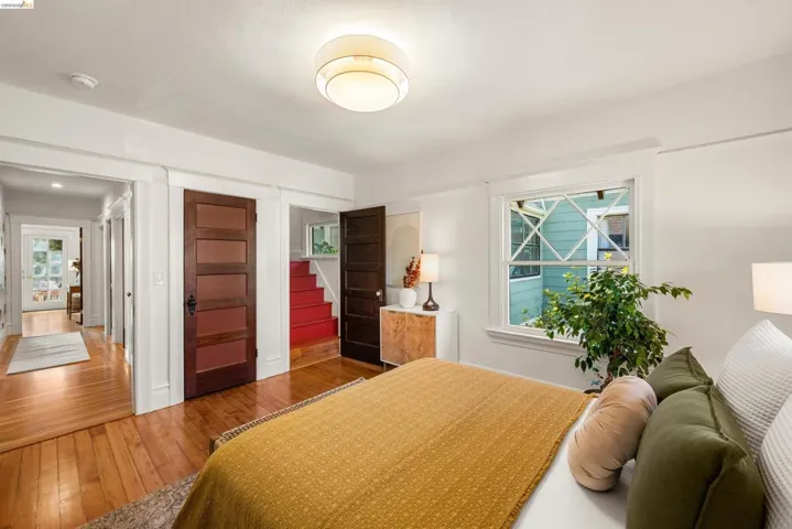 Hardwood flooring throughout, featuring a five-panel interior door and a red staircase