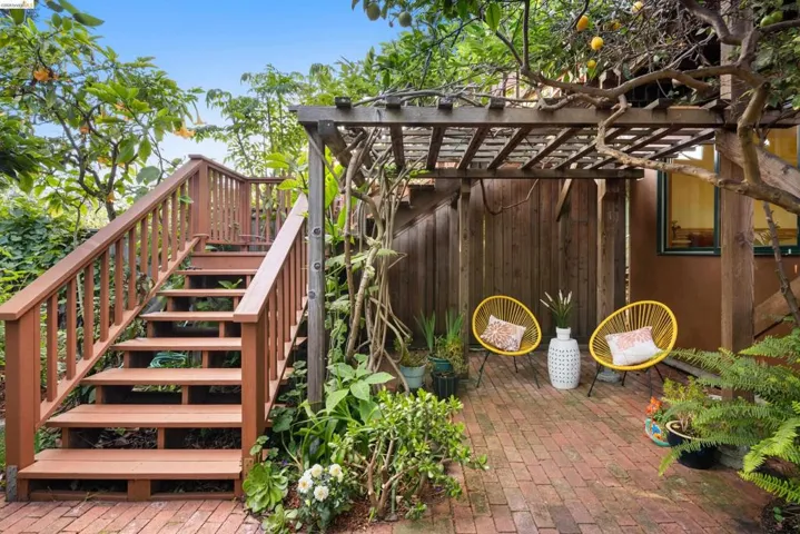 Outdoor patio space featuring a brick paver surface, a wood pergola structure, and a staircase with wood railings