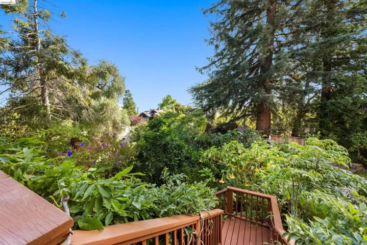 Wood-finish deck with railing, surrounded by mature trees and lush landscaping