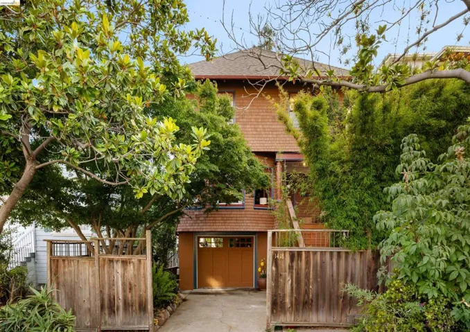 Split-level residence featuring a shingle exterior and a terracotta-colored garage door