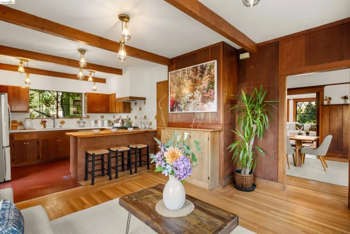 Open concept living area featuring exposed wood ceiling beams and wood-finish flooring