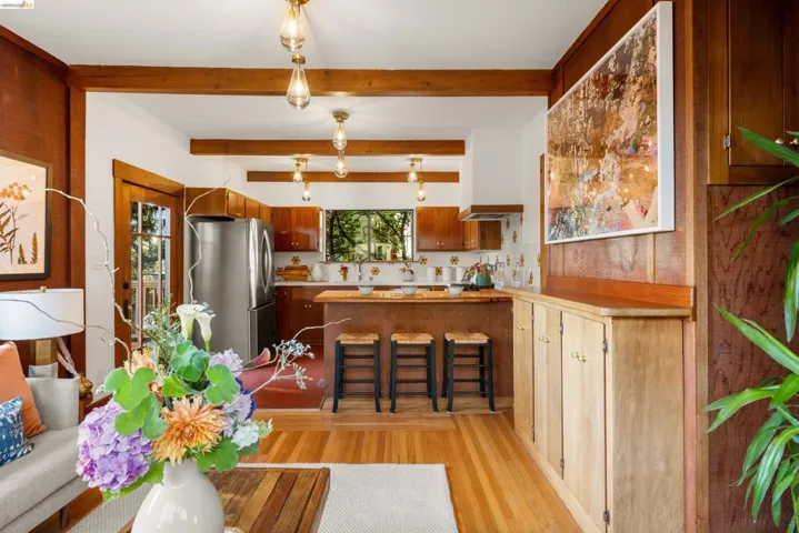 Kitchen and living area featuring exposed wood beams and wood-finish flooring