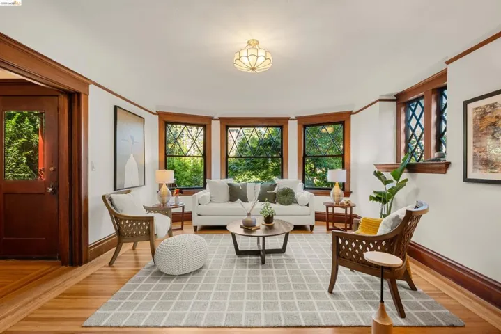 Living area featuring wood-finish flooring, a bay window with multiple panes, and a wood-trimmed entry door with glass paneling