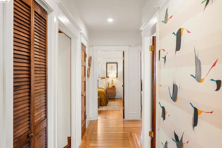 Hallway featuring wood-finish flooring, white trim, recessed lighting, and a decorative wall treatment