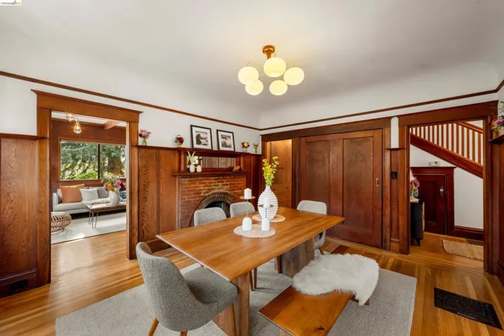 Dining area featuring wood-finish flooring, a brick fireplace with a mantel, and wood-paneled walls