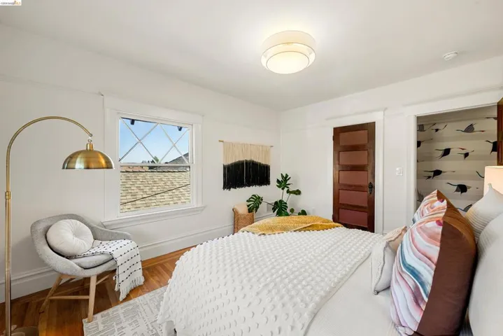 Bright interior space featuring wood-finish flooring, a multi-pane window with cross-grids, a dark wood panel door, and a built-in recessed closet