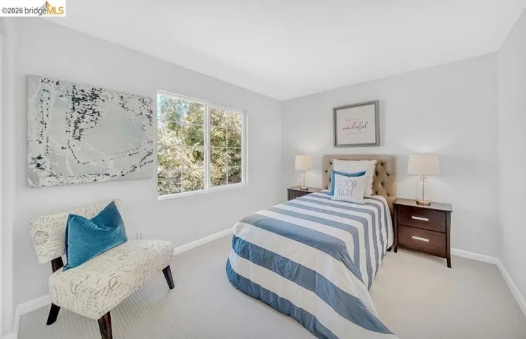 Bright room featuring a large window, light-toned walls, and neutral carpeting