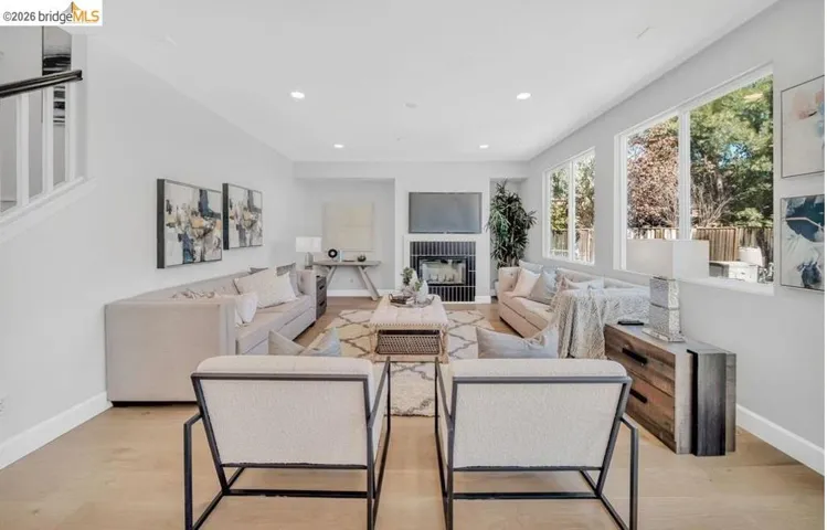 Spacious living area featuring light wood-finish flooring, recessed lighting, and a linear fireplace with a dark tile surround