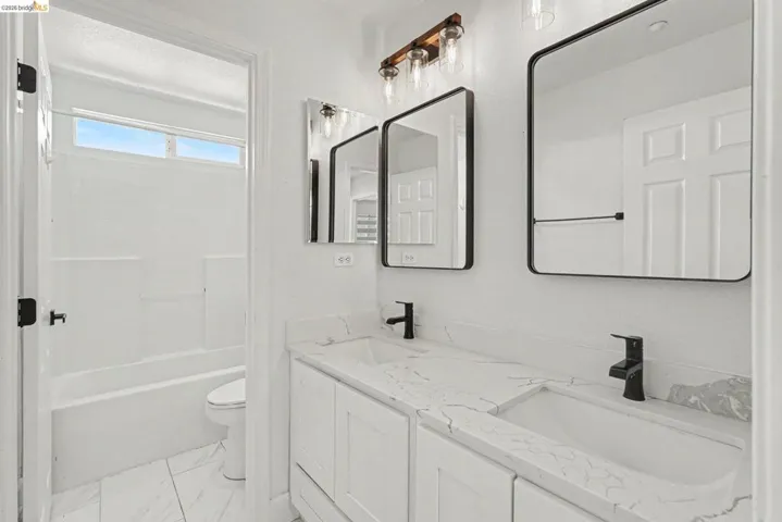 Dual vanity with integrated sinks, white cabinetry, and a light-toned countertop with veining