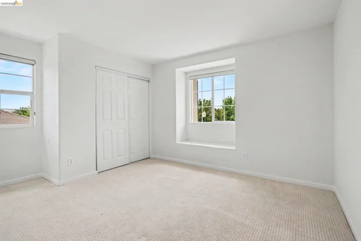 Bright room featuring neutral carpeting, white walls, and two windows