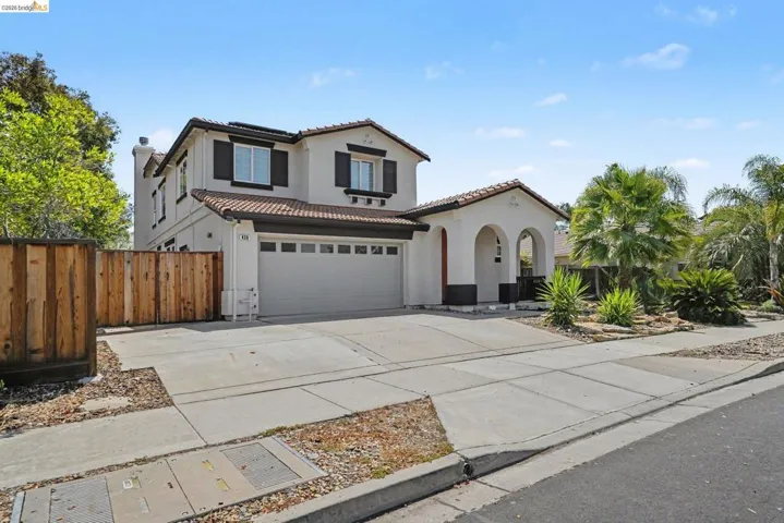 Contemporary stucco exterior with a tiled roof, arched entryway, and a two-car garage