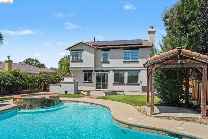 Rear exterior featuring a stucco finish, tile roof, and solar panels