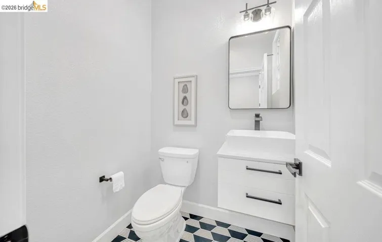 Powder room featuring a modern floating vanity with vessel sink, matte black faucet, and geometric patterned floor tiling