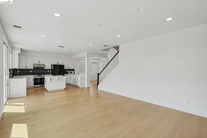 Open-concept main living area with wood-finish flooring, recessed lighting, and a white color palette