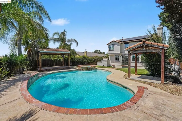 Freeform swimming pool with brick coping and adjacent spa