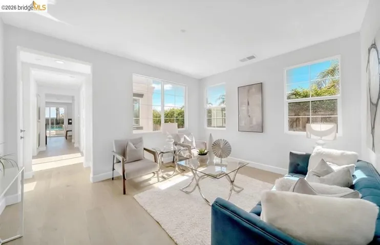 Bright living area featuring wood-finish flooring, white walls, and multiple windows