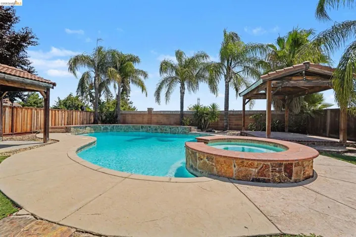Outdoor oasis featuring a freeform swimming pool, integrated spa with stone surround, and concrete patio