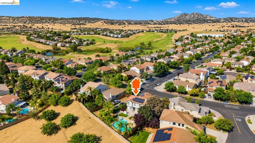 Aerial perspective showcasing the residential community with a golf course and natural hills backdrop