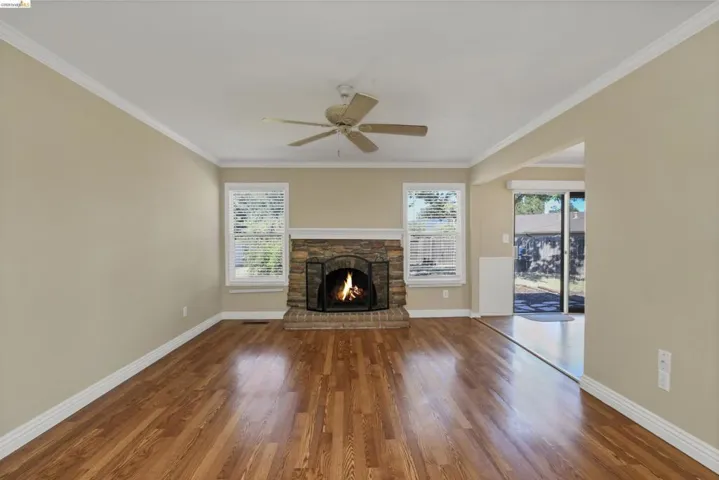 Living area featuring wood-finish flooring and a stone-clad fireplace with a brick hearth