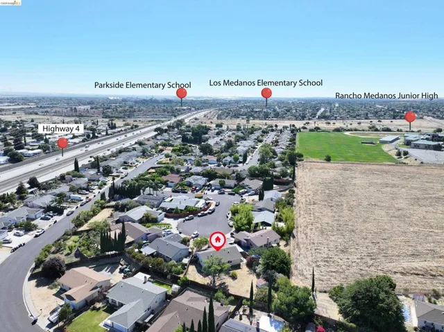 Aerial view of a residential neighborhood with single-story homes, surrounded by mature trees and established landscaping