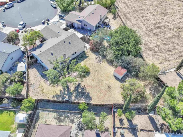 Expansive rear yard featuring mature trees, a storage shed, and perimeter fencing