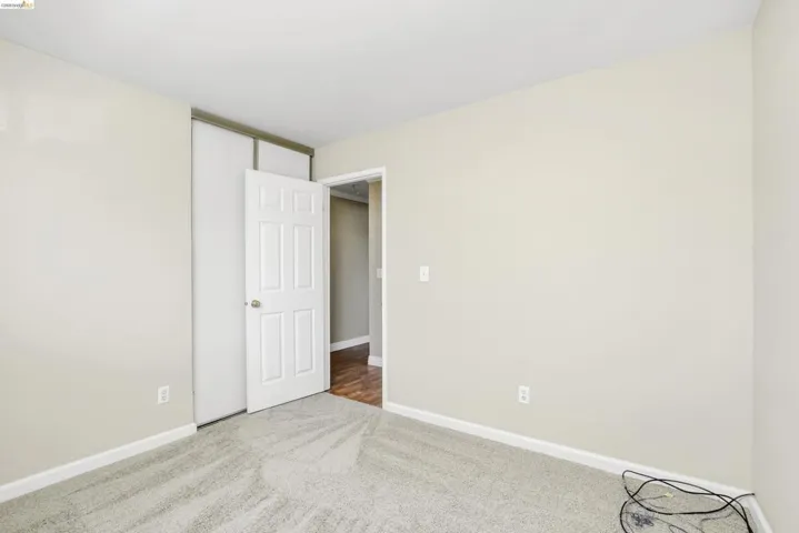 Carpeted room with neutral walls, white trim, and a paneled door