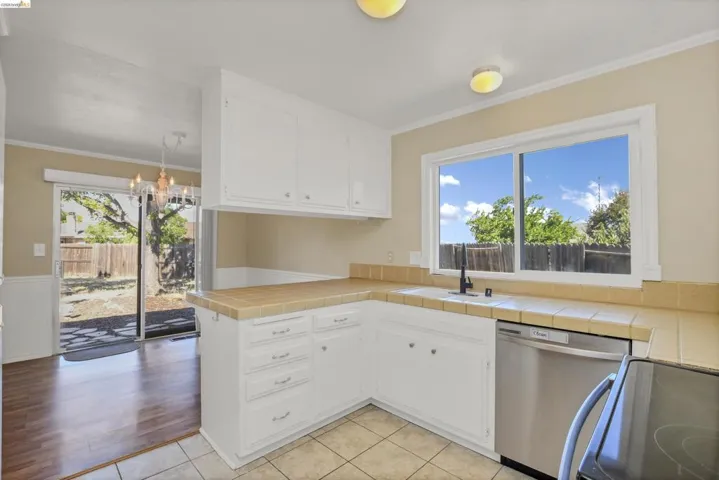 Kitchen featuring white cabinetry, tile countertops, and a stainless steel dishwasher