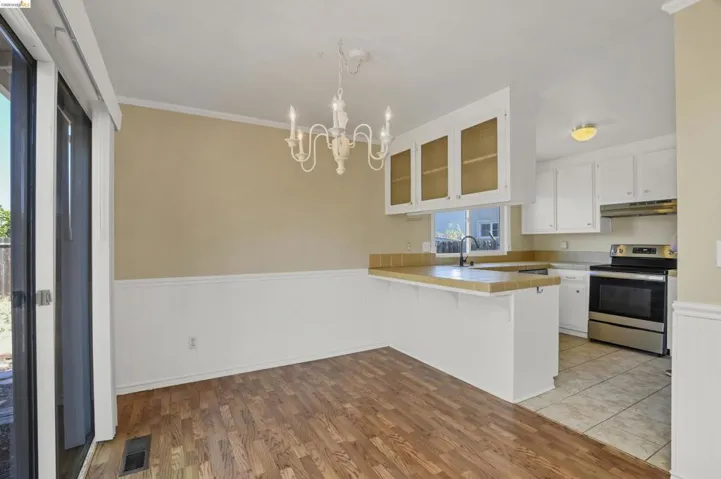 Dining area featuring wood-finish flooring, wainscoting, and a white chandelier