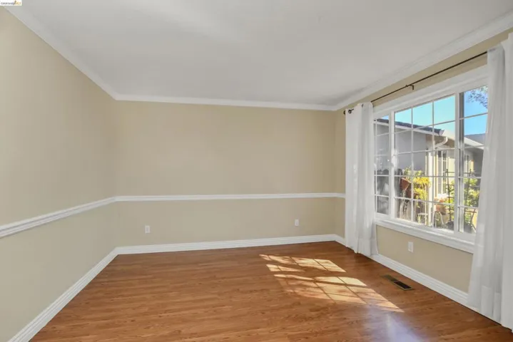 Bright interior space featuring wood-finish flooring, neutral wall tones, and extensive white crown molding