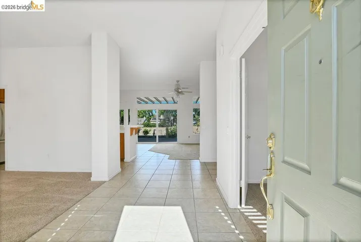 Entryway with light-toned tiled flooring, featuring a paneled door with brass hardware