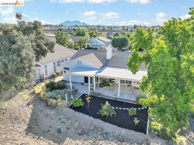 Expansive rear patio area featuring a covered pergola and concrete surfacing