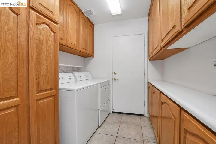 Dedicated utility space featuring ample wood cabinetry, a practical countertop, and tile flooring