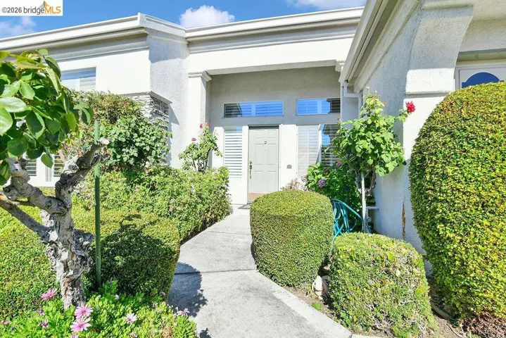 Stucco exterior with a recessed entryway, featuring a light-colored front door with sidelight windows