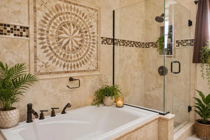 Beautiful custom bathroom with stone and granite finishes, double sinks, soaking tub. Warm lighting.