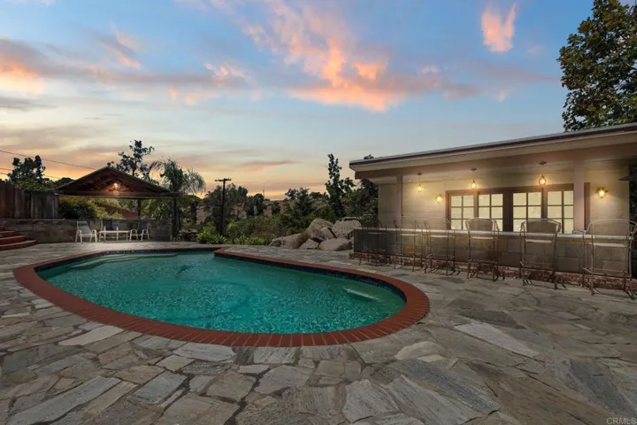 Enhanced twilight photo. Enertainers paradise with a bar area, detached poolhouse with a bathroom.