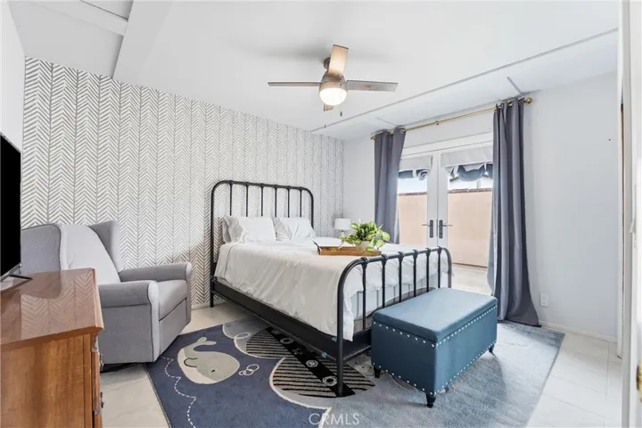 Guest bedroom with ceiling fan and doors to front courtyard.