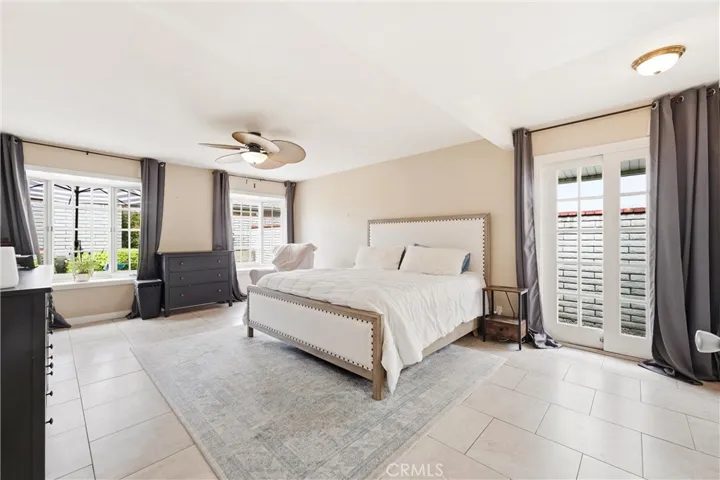 Primary bedroom with easy access to the outside with French doors and French windows and ceiling fan.