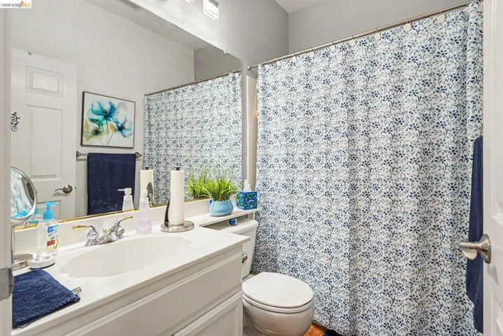 Bathroom featuring a single vanity with an integrated sink, polished chrome faucet, and expansive wall mirror