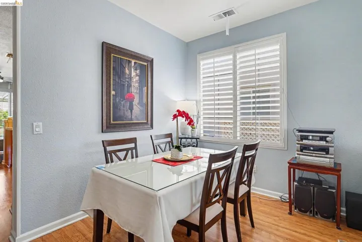 Dining area featuring wood-finish flooring and a window with plantation shutters