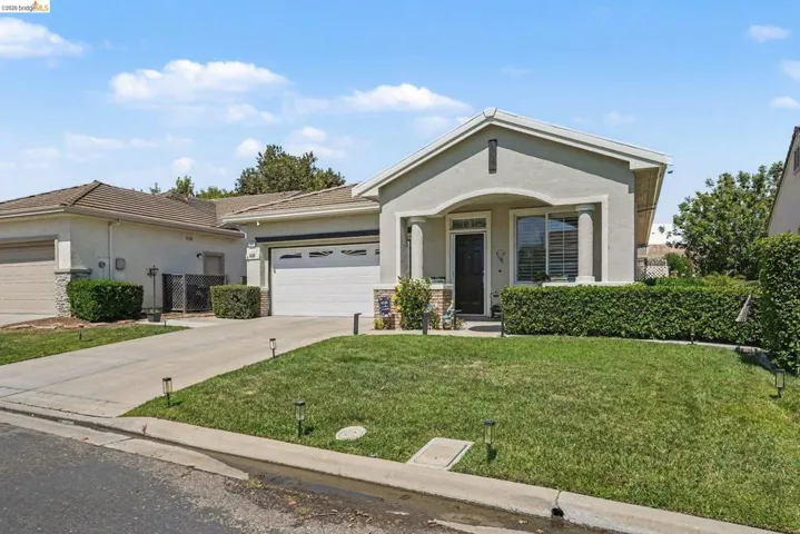 Stucco exterior residence with an attached two-car garage, concrete driveway, and front lawn